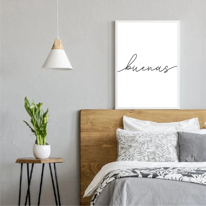 Modern bedroom with wooden headboard, 'buenas' artwork, and small table with plant.