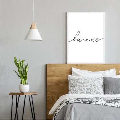 Modern bedroom with wooden headboard, 'buenas' artwork, and small table with plant.