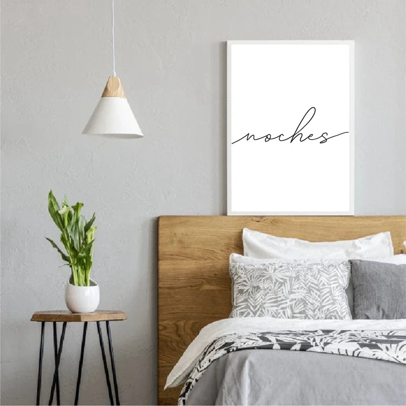 Modern bedroom with wooden headboard, white bedding, and 'noches' wall art.