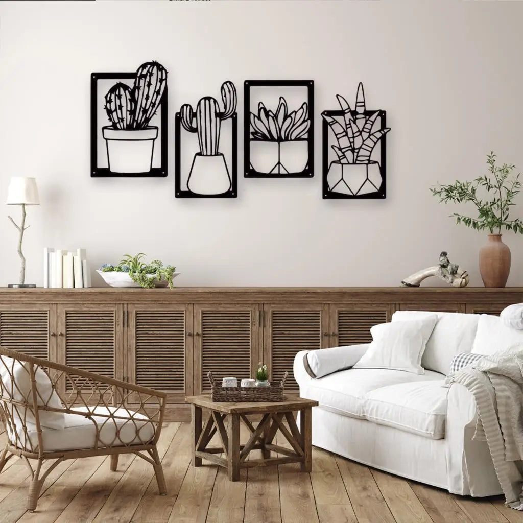 Four black metal wall art frames depicting different cacti and succulents, displayed on a light beige wall above a wooden console table in a styled living room.