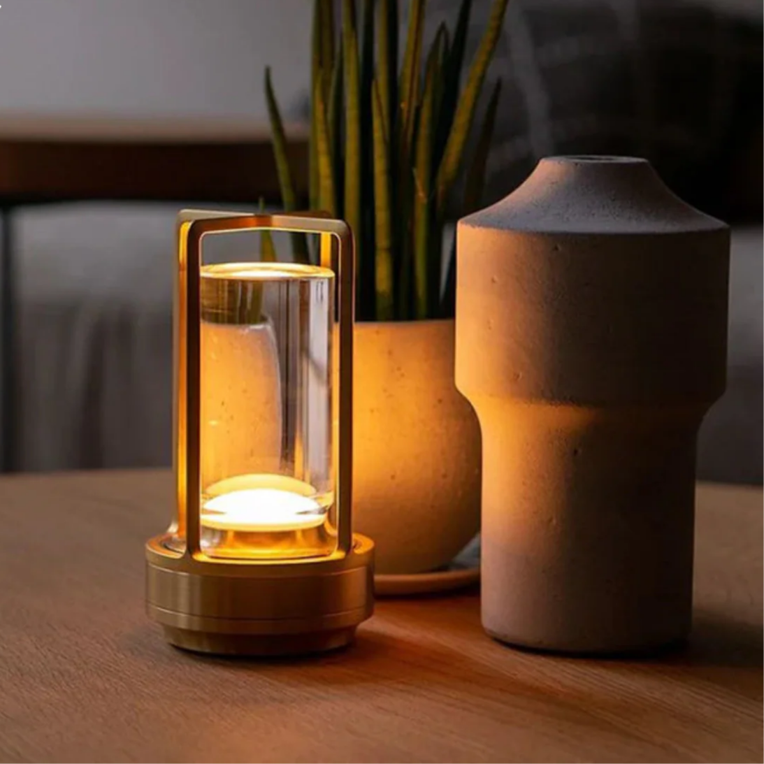 Small lamp with a warm glow on a wooden surface next to a plant and a textured vase.