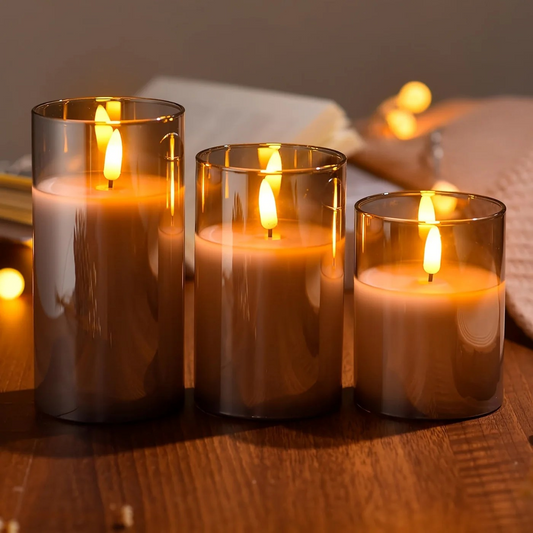 Three lit candles in glass holders on a wooden surface with a blurred background