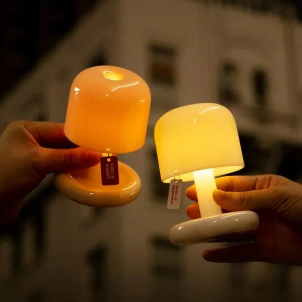 Two small, round lamps held by hands with a blurred background
