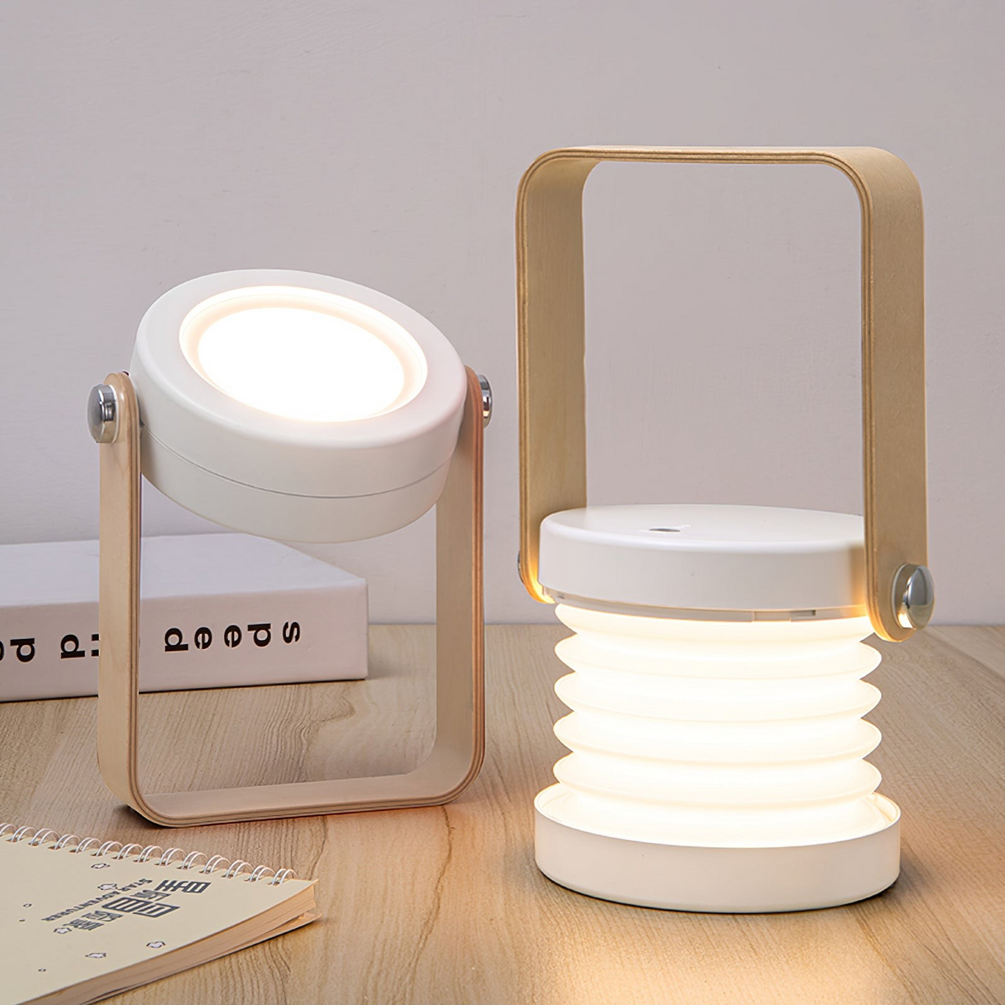 Two portable lamps with wooden handles on a light wooden surface.