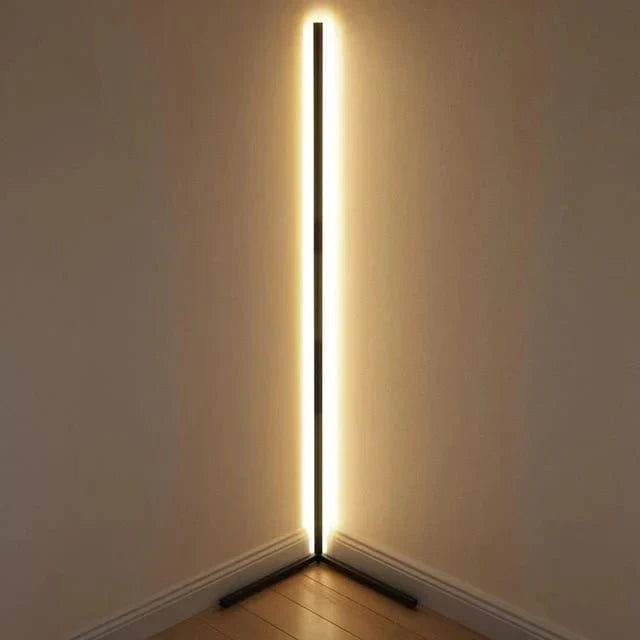 Modern floor lamp with a long, thin light source against a plain wall.